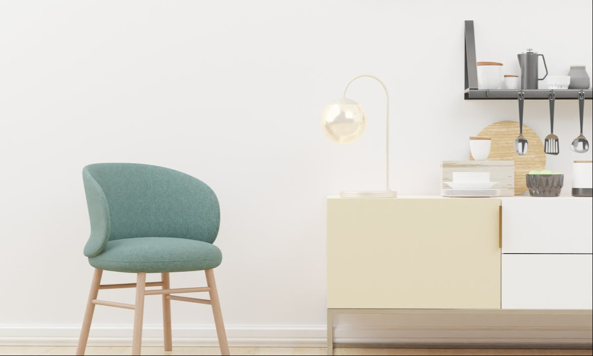 Green chair in a room with a white wall and a small table with decorative items.